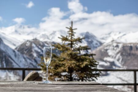 Glass of Champagne on the background of winter mountain landscape and New Year tree (spruce)