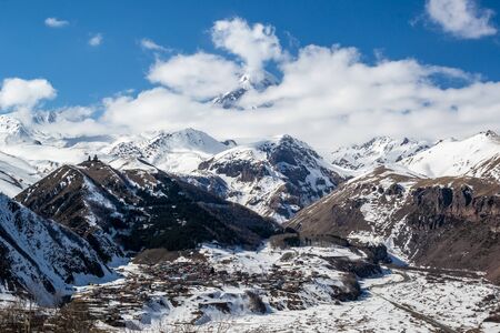 Scenic winter panoramic view from terrace of hotel in Stepantsminda on Kazbek mountain and Gergeti...