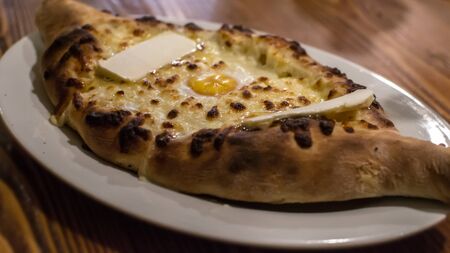 Hot adjarian khachapuri served on a white plate in a restaurant in Georgiaの写真素材