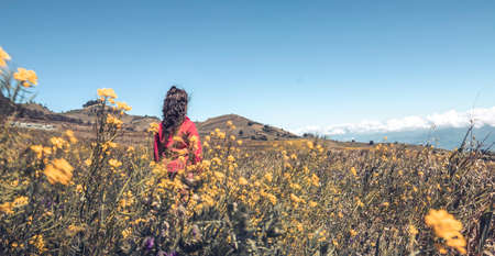 yung girl looking at the horizon surrounded by flowersの写真素材
