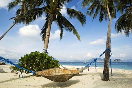 Rattan hammock along white beach in the Philippinesの写真素材