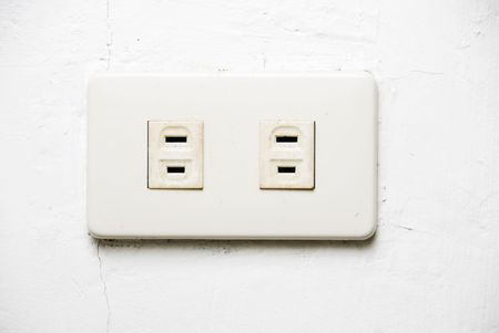 White wall socket on uneven and dirty white wallの写真素材