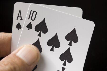 Blackjack cards held by hand against black background