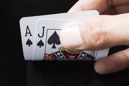 Blackjack cards held by hand against black background