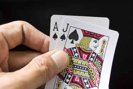 Blackjack cards held by hand against black backgroundのeditorial素材