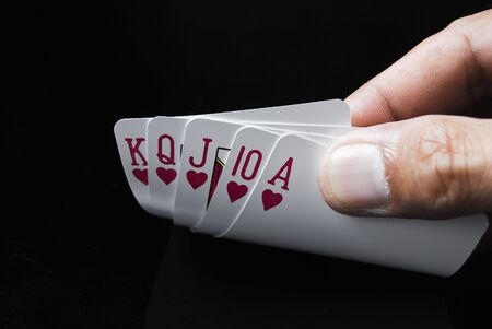 Royal Flush held by hand against black backgroundの写真素材
