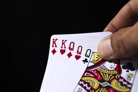 Three Kings and three Queens held by hand against black backgroundの写真素材