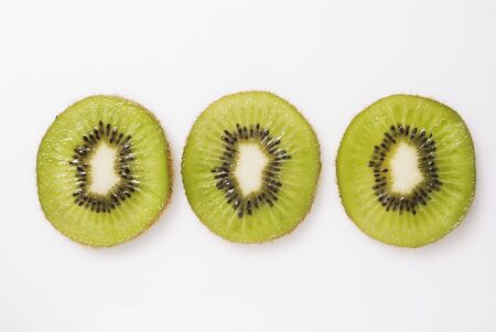 Three slices of kiwi fruit on white backgroundの写真素材