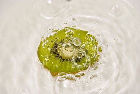 Slice of kiwi fruit and water on white backgroundの写真素材