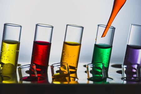 A line of test tubes containing different colored liquidsの写真素材