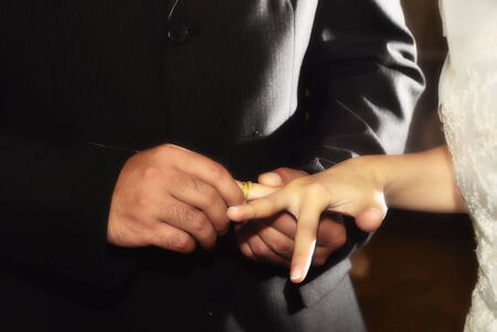 Groom giving his ring to bride during a wedding ceremonyの写真素材