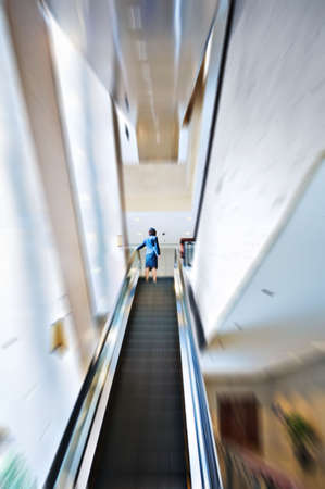 Business woman moving up on escalatorの写真素材