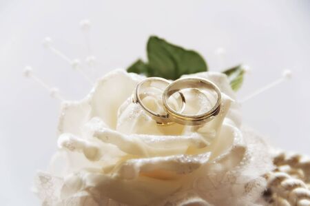 Gold wedding rings on a white rose made of clothの写真素材