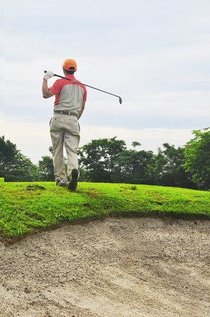 Golf player with back towards the camera after hitting the ballの写真素材