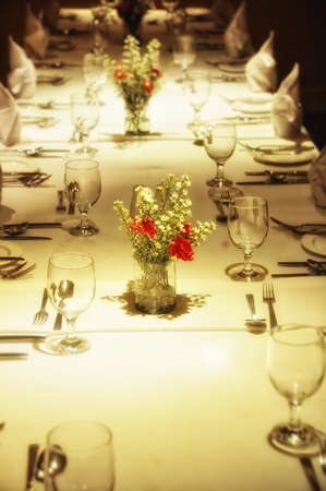 Close up of formal place setting. Focus red flowers at foreground