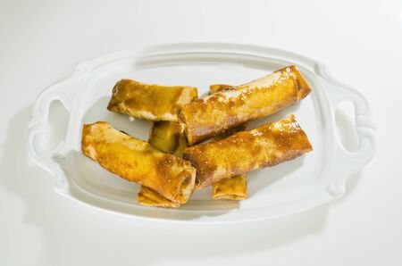 Fried bananas in spring roll and brown sugar syrup on white serving plate