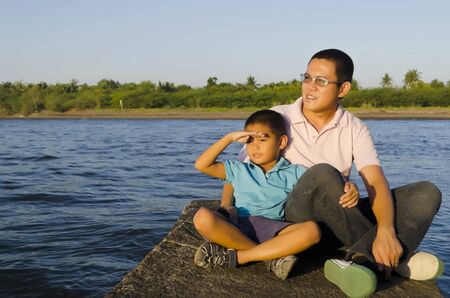 Father and son on a jetty watching sunsetの写真素材