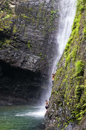 Man and boy attempt to climb a natural waterfall in a tropical forest in the Philippinesのeditorial素材