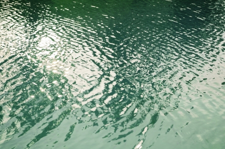 Sun reflecting on ripples of green pool waterの写真素材