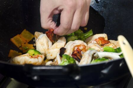 Close-up of shrimps and vegetables in wok with wooden spoonの写真素材