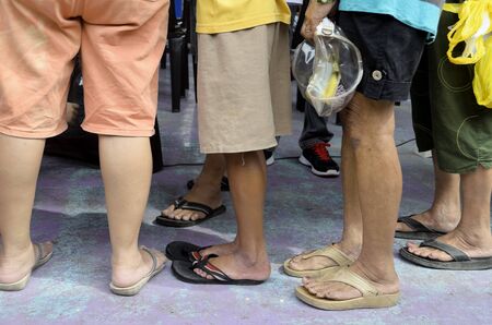 Matured women wearing mostly slippers and shorts standing in lineの写真素材