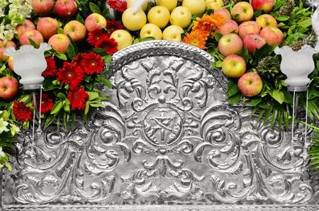 Detail of an old hammered aluminum religious art decorated with apples and flowers.の写真素材