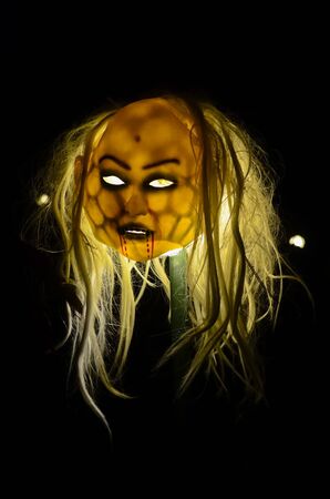 Halloween zombie mask on a stick and shot against black backgroundの写真素材