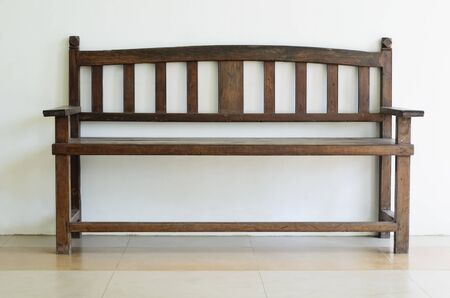 Old wooden bench shot against plain wall