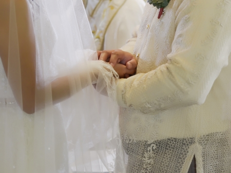 Closeup of bride and groom holding hands during a wedding ceremonyの写真素材