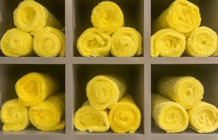 Stack of rolled yellow towels inside locker roomの写真素材
