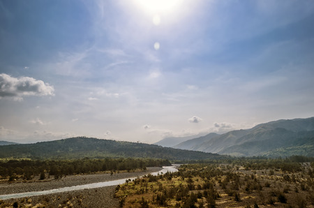 Sun shining over mountains and riverの写真素材
