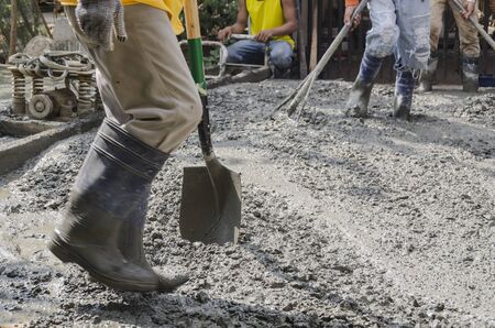 Men levelling newly poured road concrete mixの写真素材