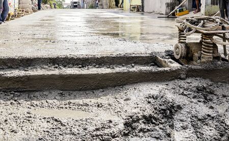 Construction men standing on the side of a road with newly poured concrete mixの写真素材