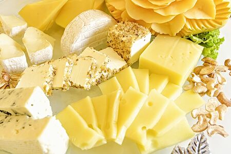 Different kinds of cheese with cashew nuts and fruit on tableの写真素材