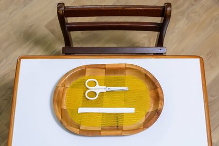 Toddlersâ school desk and chair with scissors and a piece of white paper on a trayの写真素材