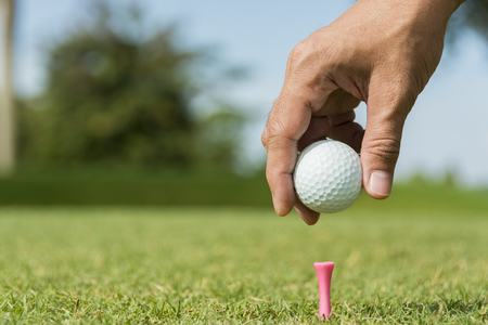 Male caddie putting golf ball on pink pegの写真素材