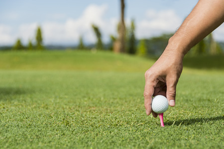Male caddie putting golf ball on pink pegの写真素材