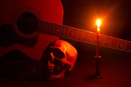 Human skull and guitar in candlelight on a wooden tableの写真素材