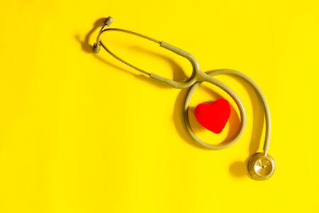 red heart with stethoscope, heart health, health insurance concept on  yellow backgroundの写真素材