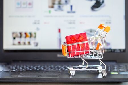Online shopping concept. Shopping cart, small boxes, laptop on the deskの写真素材