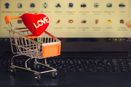 Red heart in a trolley on a laptop keyboard. Ideas about online shopping, online shopping is a form of electronic commerce that allows consumers to directly buy goods from a seller over the internet.の写真素材