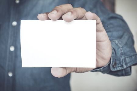 Man holding white business card on concrete wall backgroundの写真素材