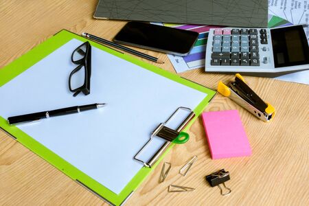 Businessman working on a laptop at office desk with paperwork and other objects around