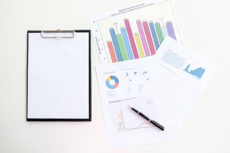 top view of business chart on white wooden table with notebook and pen.の写真素材