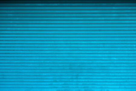 Metal curtain door texture. Background of the store with closed metal blue curtainsの写真素材
