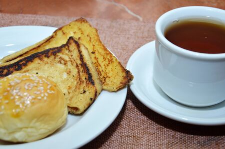 toast on white plate and a cup of tea