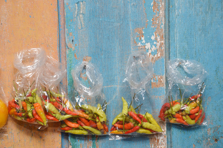 Retail sale of fruit chili in plastic bags hanging wooden wallの写真素材