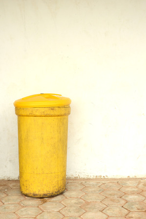 a yellow plactic trash can against the wallの写真素材