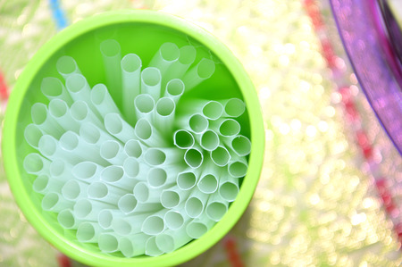 white drinking straws on the green plastic glassの写真素材