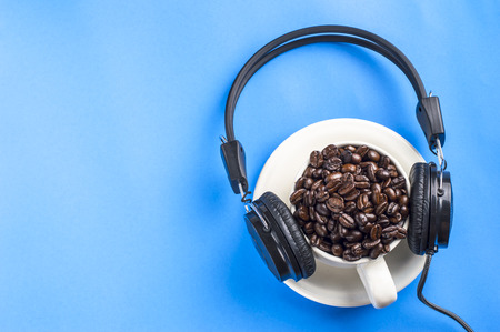 coffee beans on the white cup with black headphone at blue backgroundの写真素材